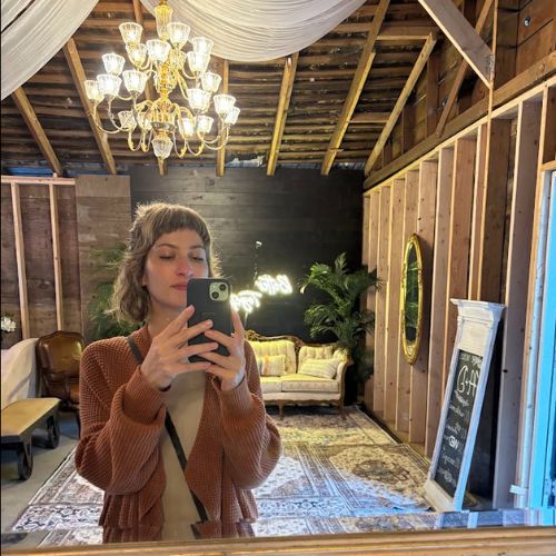 Kala taking a mirror selfie in a warmly lit reading room