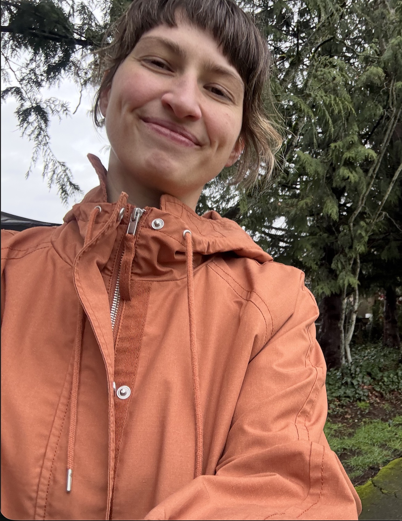 Kala smiling outdoors in an orange jacket